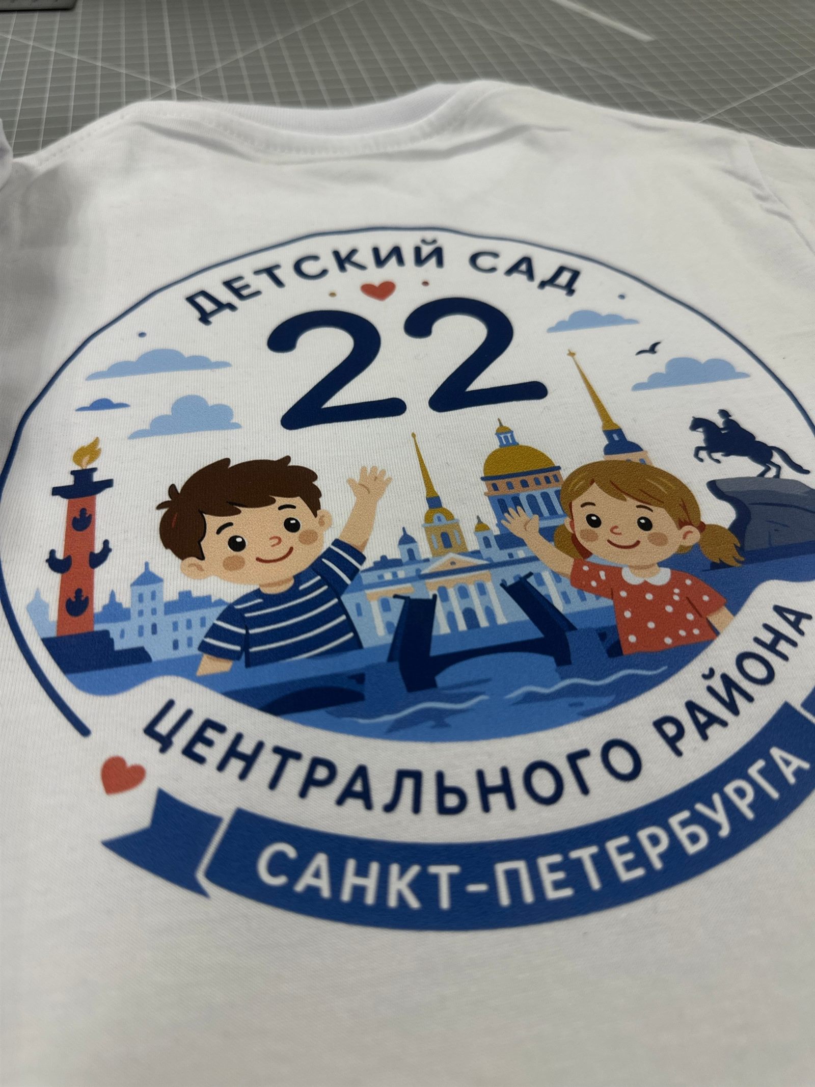 Крупный план цветного принта детского сада № 22 на белой футболке